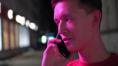 Young cute boy talking on smartphone on the street at night, 4k Stock Footage 95842896
