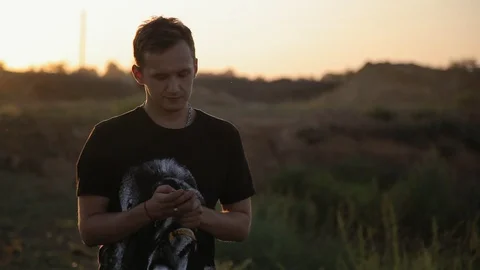 Young cute boy using cell phone in the field at sunset Vidéo 94442434