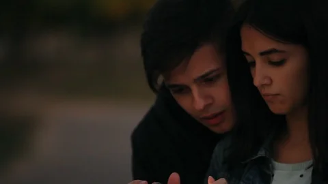 Young cute couple using smartphone in the evening park Видео 97181850