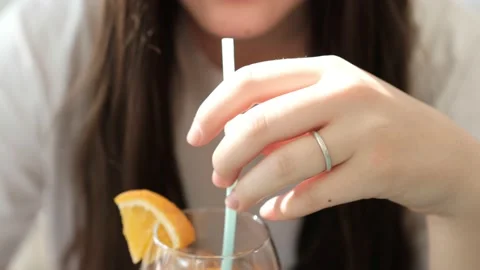 Young cute girl eagerly drinks a cocktail from the straw. Close up. Stock Footage 162938347