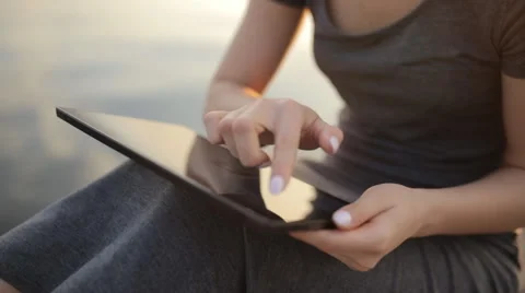 Young cute girl with tablet computer sitting close to the river Stock Footage 66554538