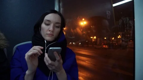 Young cute girl using smart phone with headphones during bus ride Stock Footage 83872871