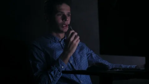 Young cute man vaping in front of computer at home in dark room Stock Footage 99051157