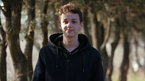 Young cute man walking among trees trunks and relaxing in the park Video stock 105080764