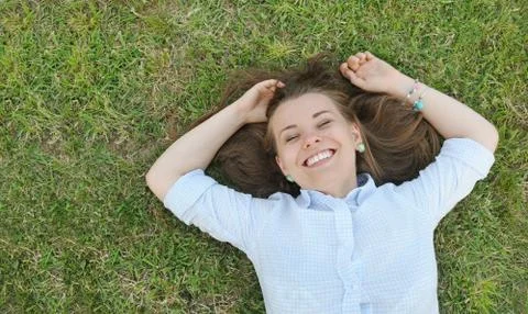 Young cute student having fun on the grass in the park Stock Photos