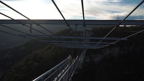Young cutie run through modern cable bridge. Happy mood on autumn vacation Vidéo 107917825