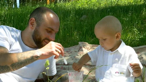 Young dad and son sharing ice cream in the park and smiling slow motion Stock Footage 96331015