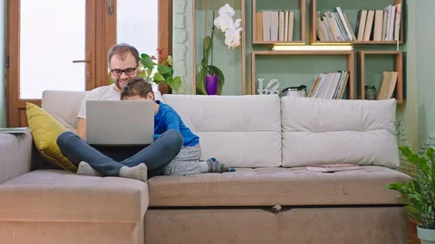 Young dad with his small charismatic son spending happy time on the sofa they Video stock 127909161