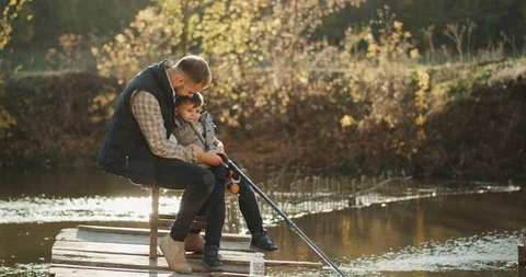 Young dad with his son fishing on the lake they have a happy mood smiling Stock Footage