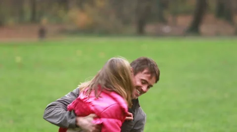 Young dad holding daughter in his arms and laughing in park Stock Footage 59554550