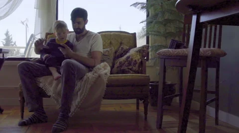 Young dad points out thing on cell phone to cute child Stock Footage 64384310