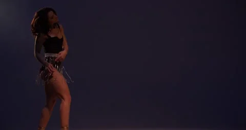 Young dancer in black one piece and silver belt is dancing, low lighting, 4k Stock Footage 147731133