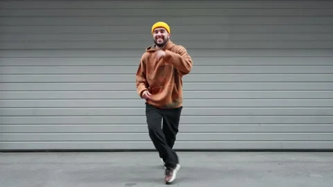 Young dancer male dancing move yellow beanie and patterned hoodie performs Stock Footage 292555251