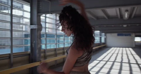 Young dancer performing inside sunlit parking building Stock Footage 213656254