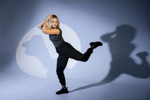 Young dancer performing with projected shadows on a light blue background Stock Photos