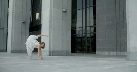 Young dancer in white dress does leg swing in slow motion outdoors, balerina Stock Footage 157452172