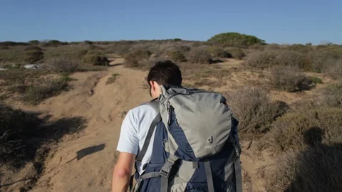 Young Dark-Haired Guy Hikes Up a Sandy Hill on a Path Near the Ocean Stock Footage 108746621