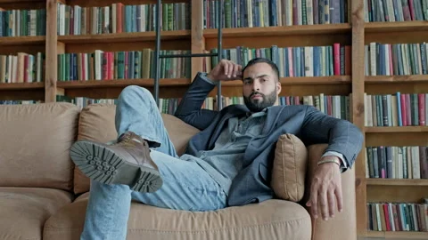 Young Dark-Haired Guy Sitting On The Couch In The Library. Stock Footage 140221637