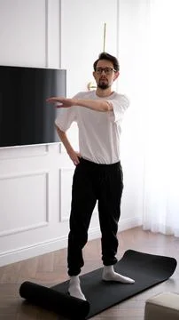 Young dark-haired man exercising at home in the early morning Foto stock