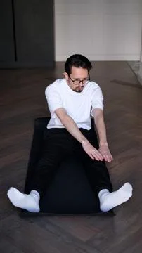Young dark-haired man exercising at home in the early morning Stock Photos