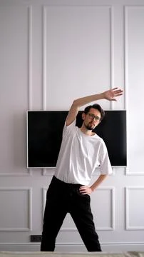 Young dark-haired man exercising at home in the early morning Stock Photos