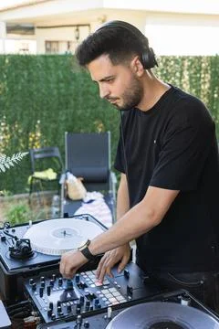 Young dark-haired man learning to use the mixer in the garden of his house .. Stock Photos