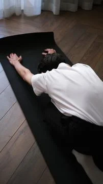 Young dark-haired man practicing yoga at home early in the morning on a mat Stock-Fotos