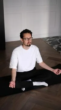 Young dark-haired man practicing yoga at home early in the morning on a mat Foto stock