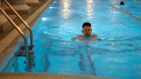 Young dark-haired man swimming in gym pool Stock Footage 333200690
