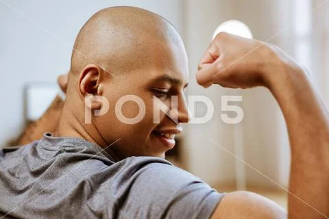 Young dark-skinned bodybuilder looking at his biceps Stock Photos