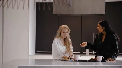 Young dark-skinned brunette and a young blonde in the kitchen in pajamas smiling Vídeo Stock 162500862