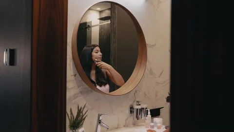 Young dark-skinned brunette in front of the mirror massages her face. Body care Video stock 162501090