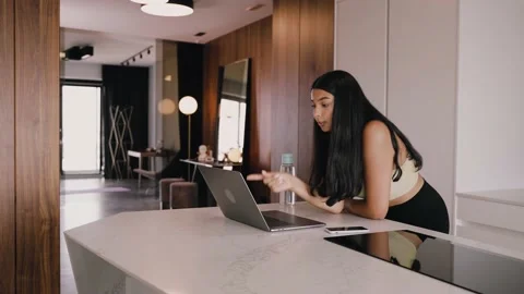 Young dark-skinned brunette in the kitchen with a laptop, video chatting Stockbeeldmateriaal 161388031
