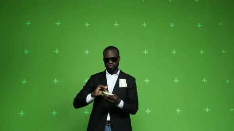 Young dark-skinned businessman is throwing dollars on chrome background. Stock Footage 130830899