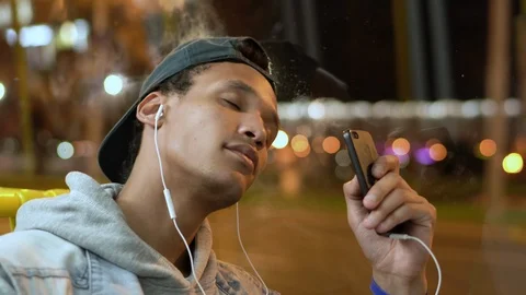 Young dark-skinned guy put on the headphones in bus and starts to relax Stock Footage 116134296