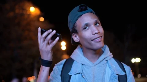 Young dark skinned guy sends and receives a voice message at night in the city Stock Footage 116152850