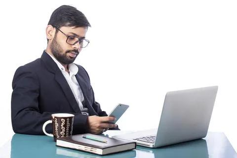 Young dashing man using mobile phone while working on computer after drinking co Foto stock