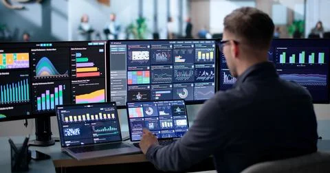 Young Data Analyst Reviews Financial Dashboard On Laptop In Office. Stock Photos