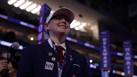 A young delegate in a white cap smiles and applauds near the Iowa, Delaware and Stock Footage 345271809