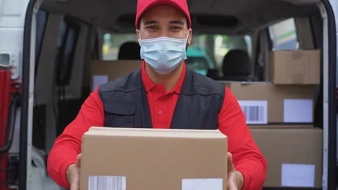 Young delivery man holding package in his hands while wearing face mask Stock Footage 145434683