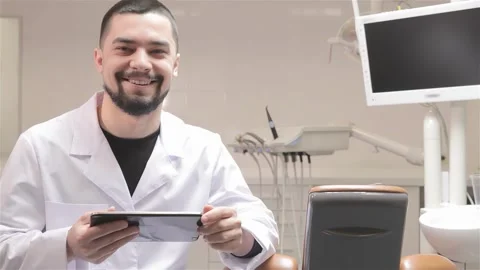 Young dentist engaged with tablet in modern dental cabinet Stock Footage 311672345