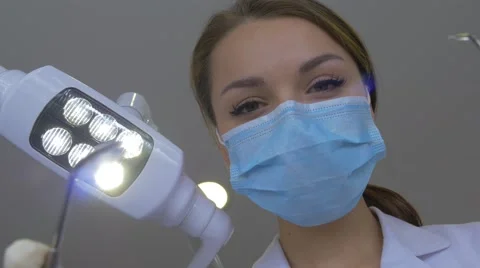 Young Dentist in Mask Approaches With a Tools Standing Upon a Patient Turns the Stock Footage 60974535