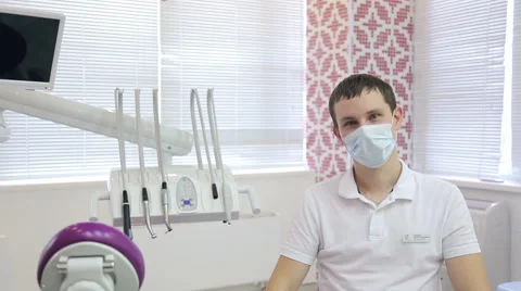 Young dentist sits in his office, next to dental setting Stock Footage 66515219