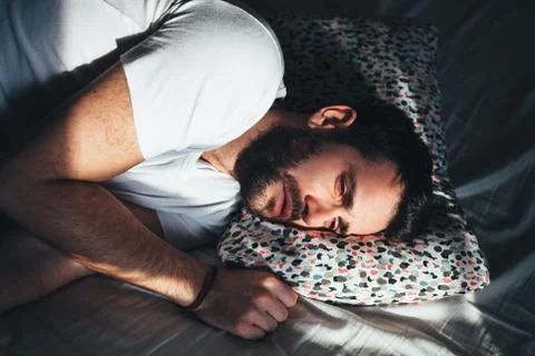 Young depressed man crying in bed Stock Photos