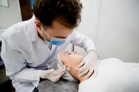Young dermatologist is making injections to solve some age-related skin problems 写真素材