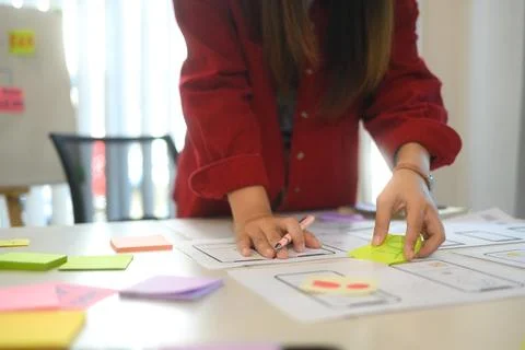 Young designer arranging sticky notes and app prototypes during a user Stock Photos
