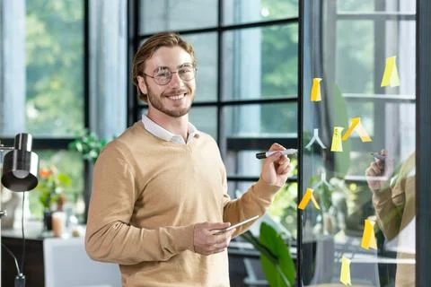 A young designer, programmer, freelancer man is standing in the office, holding Foto stock