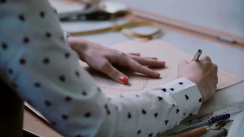 Young designer sitting at the table and draw layout of shoe on papers pattern Free Stock Footage 72835356