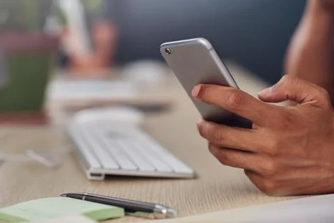 Young designer using a cellphone at his office desk Stock Photos
