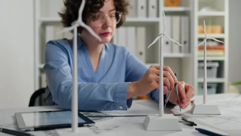 Young designer working on renewable energy project with wind turbine models Stock Footage 323716851